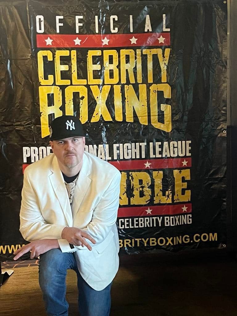 austistic rapper TU Savant posing in front of Celebrity Boxing banner